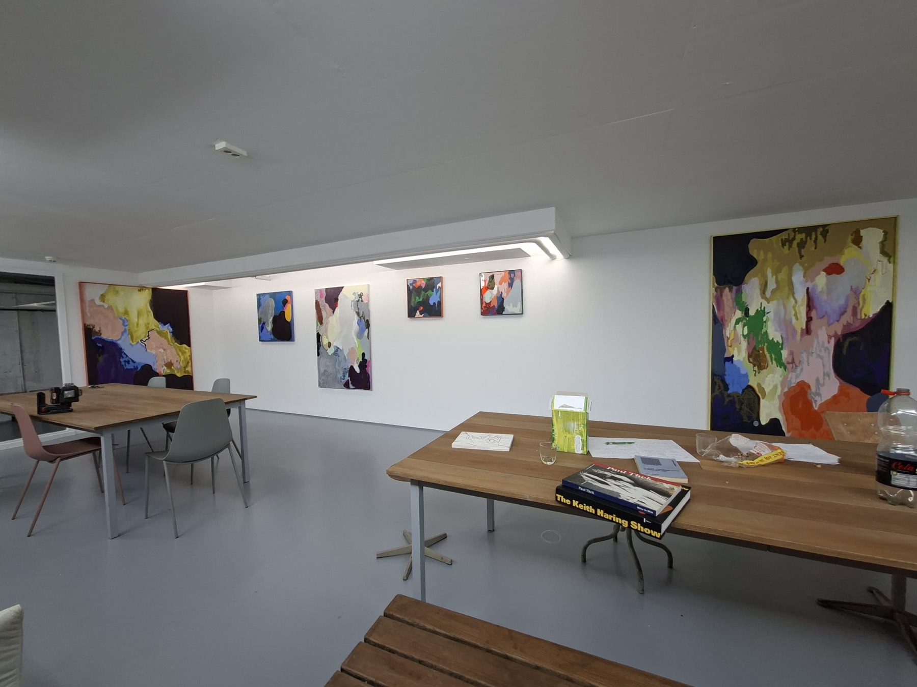 The Wall of Fine Art in de winkel van theartbook.nl, met abstracte schilderijen aan de wand en leestafels met kunstboeken